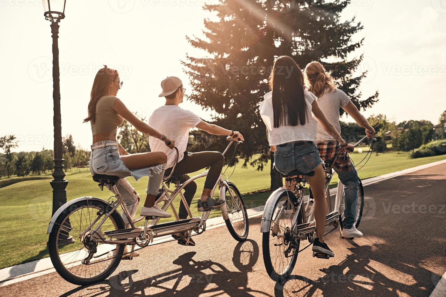 ung och full av energi. grupp av ung människor i tillfällig ha på sig cykling tillsammans medan utgifterna sorglös tid utomhus foto
