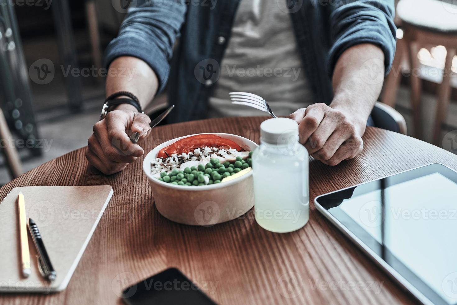 närbild av man innehav gaffel och tabell kniv medan Sammanträde i de cafeteria foto