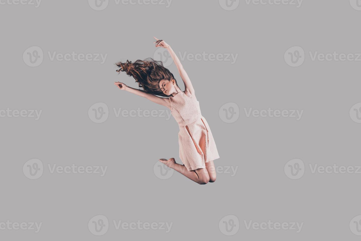 Hoppar hög. studio skott av attraktiv ung kvinna svävande i luft foto
