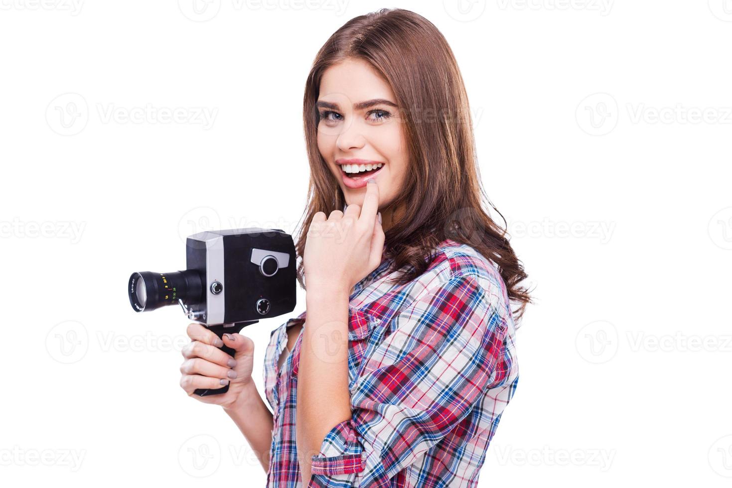 skönhet med film kamera. glad ung kvinna innehav film kamera och leende medan stående mot vit bakgrund foto