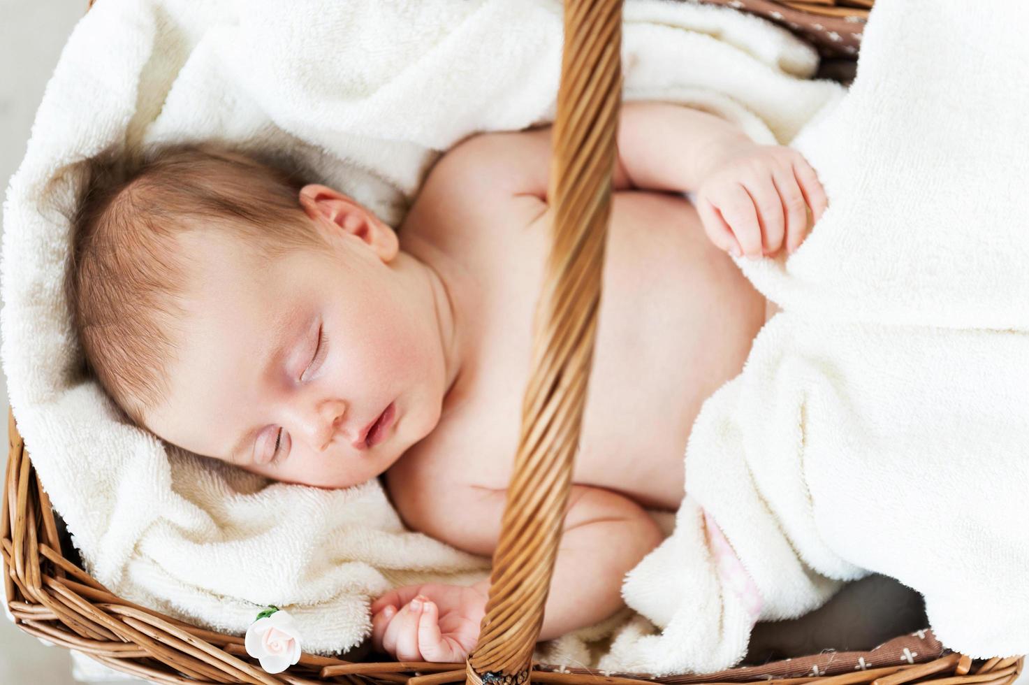 sovande i en korg. topp se av liten bebis sovande medan liggande i korg- korg och täckt med handduk foto