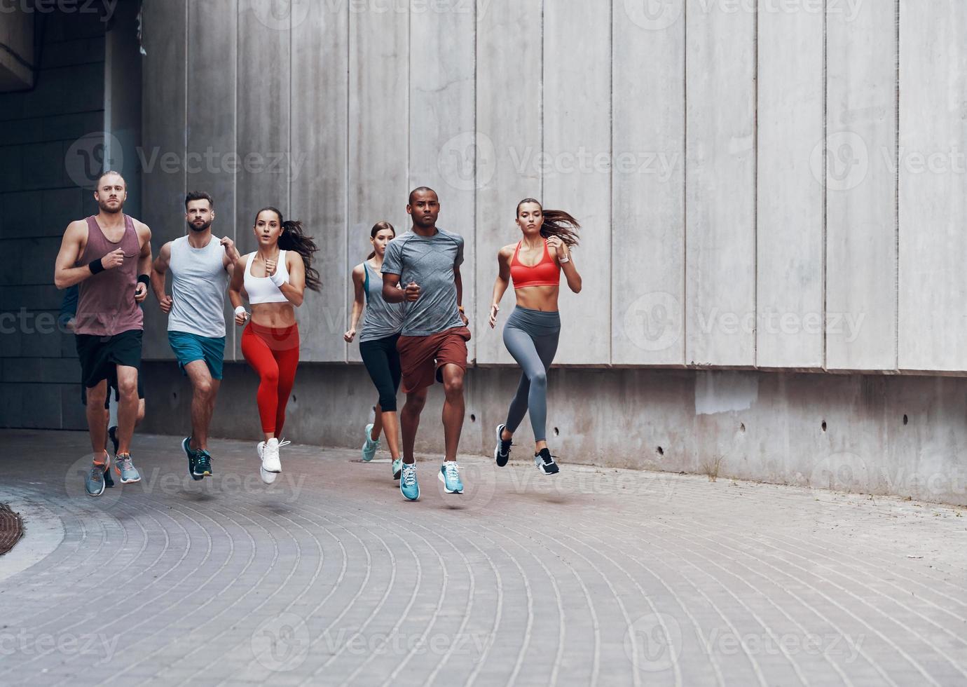 full längd av ung människor i sporter Kläder joggning medan utövar utomhus foto