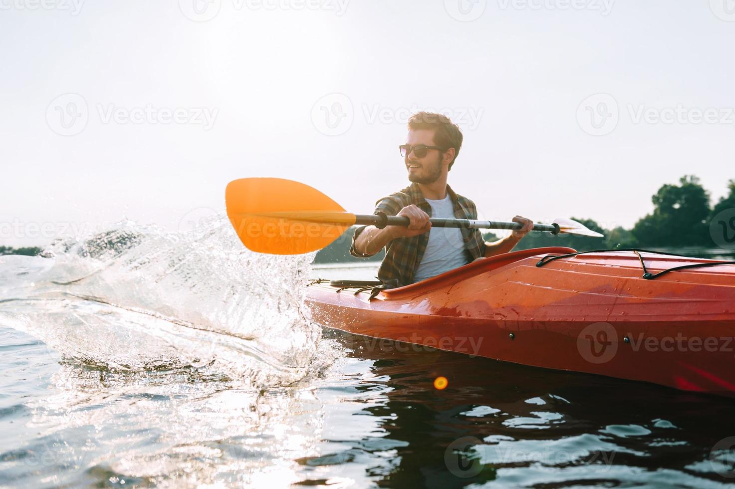 perfekt dag för Kajakpaddling. stilig ung man Kajakpaddling på sjö och leende foto