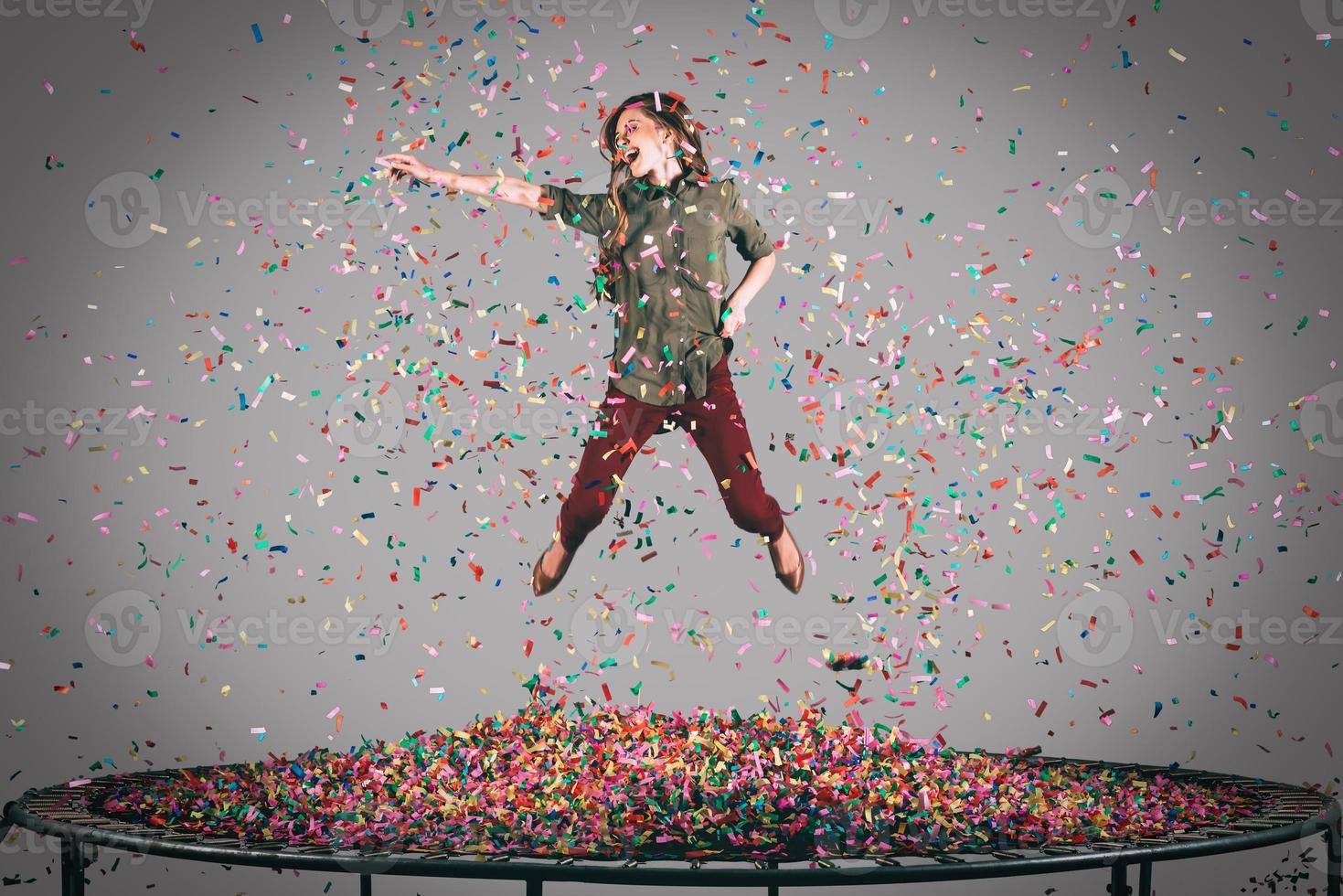 roligt i rörelse. i luften skott av skön ung kvinna Hoppar på trampolin med konfetti Allt runt om henne foto