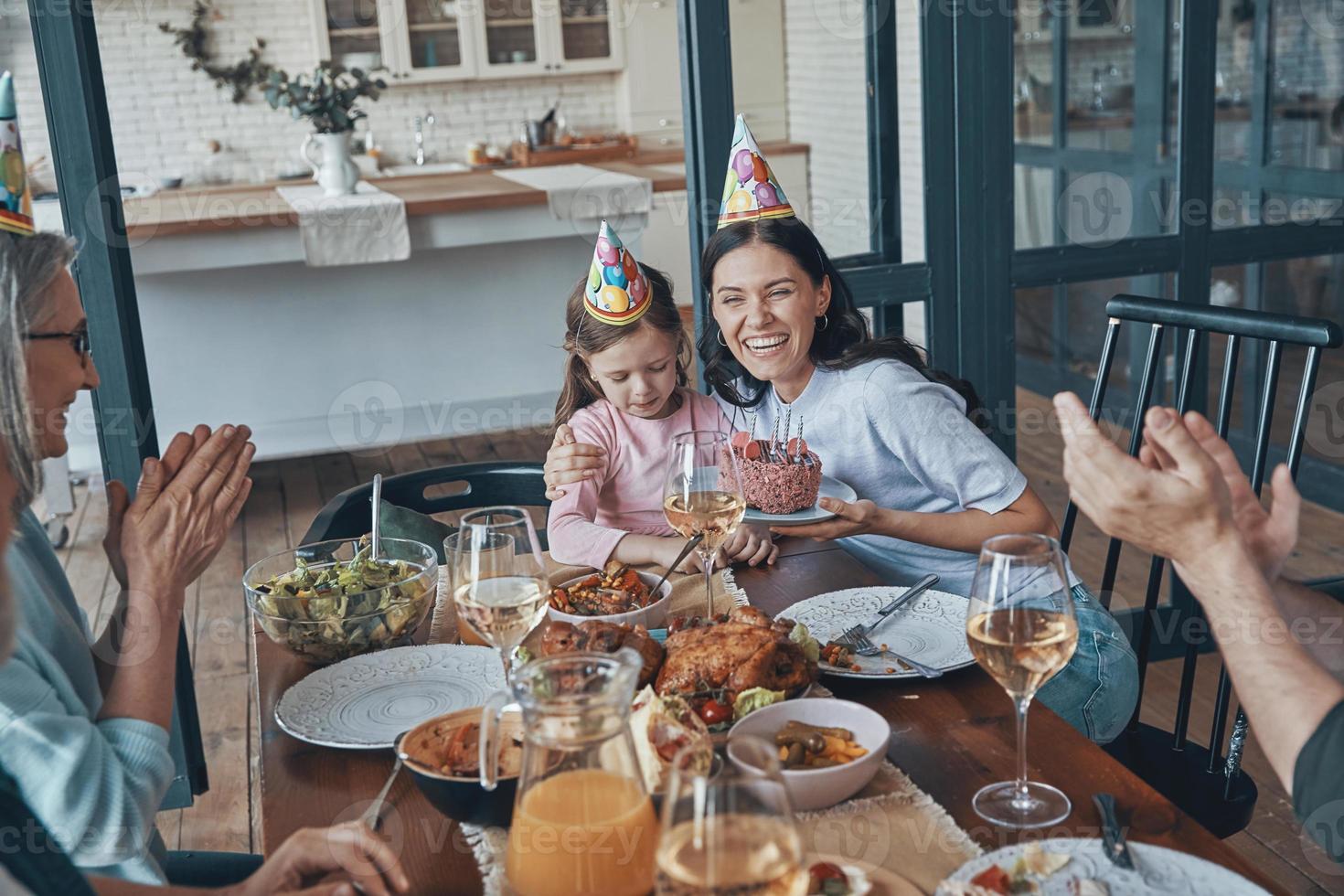 Lycklig familj fira födelsedag av liten flicka medan Sammanträde på de dining tabell på Hem foto