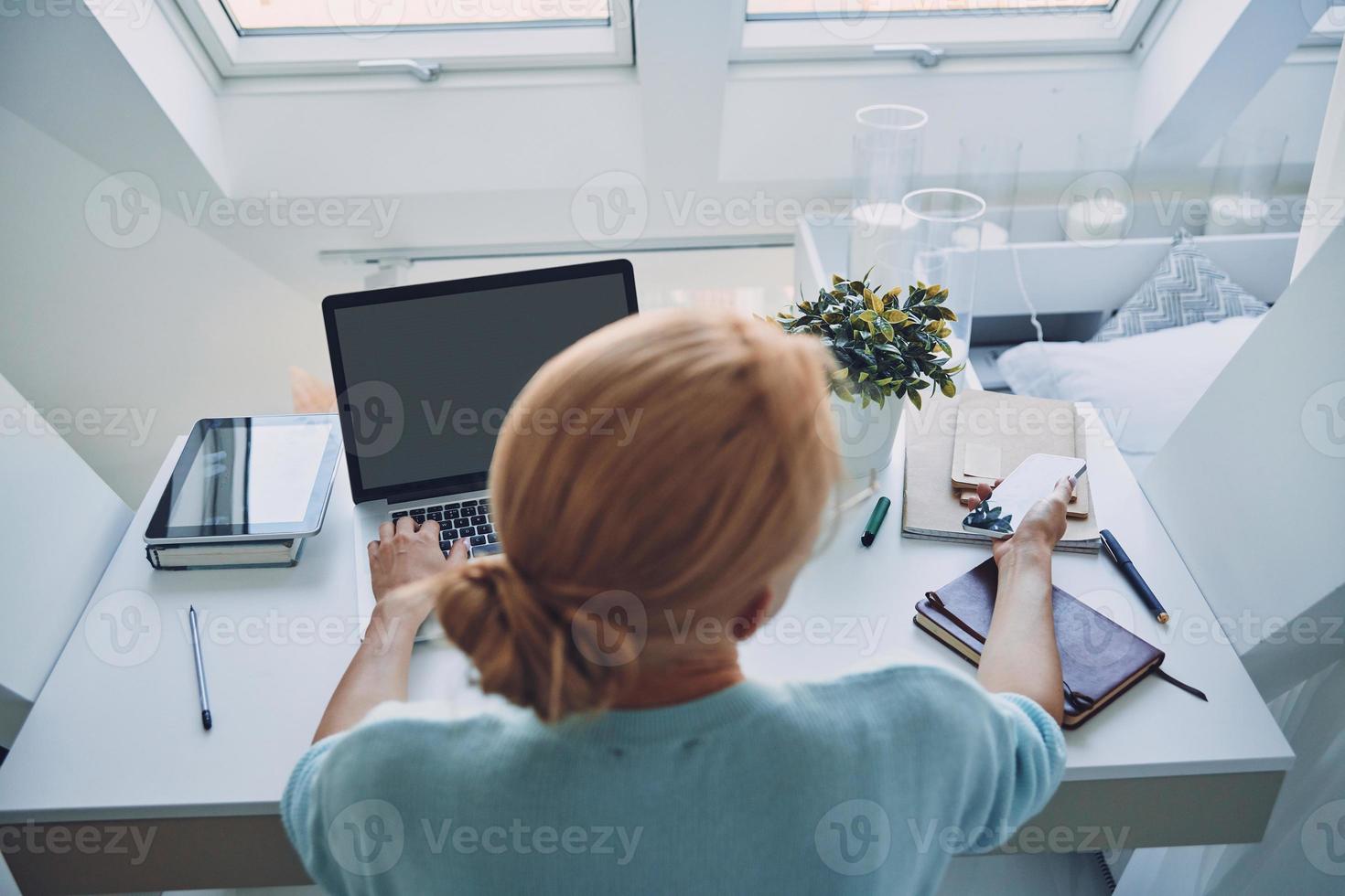 topp se av ung kvinna använder sig av teknik medan arbetssätt i kontor foto