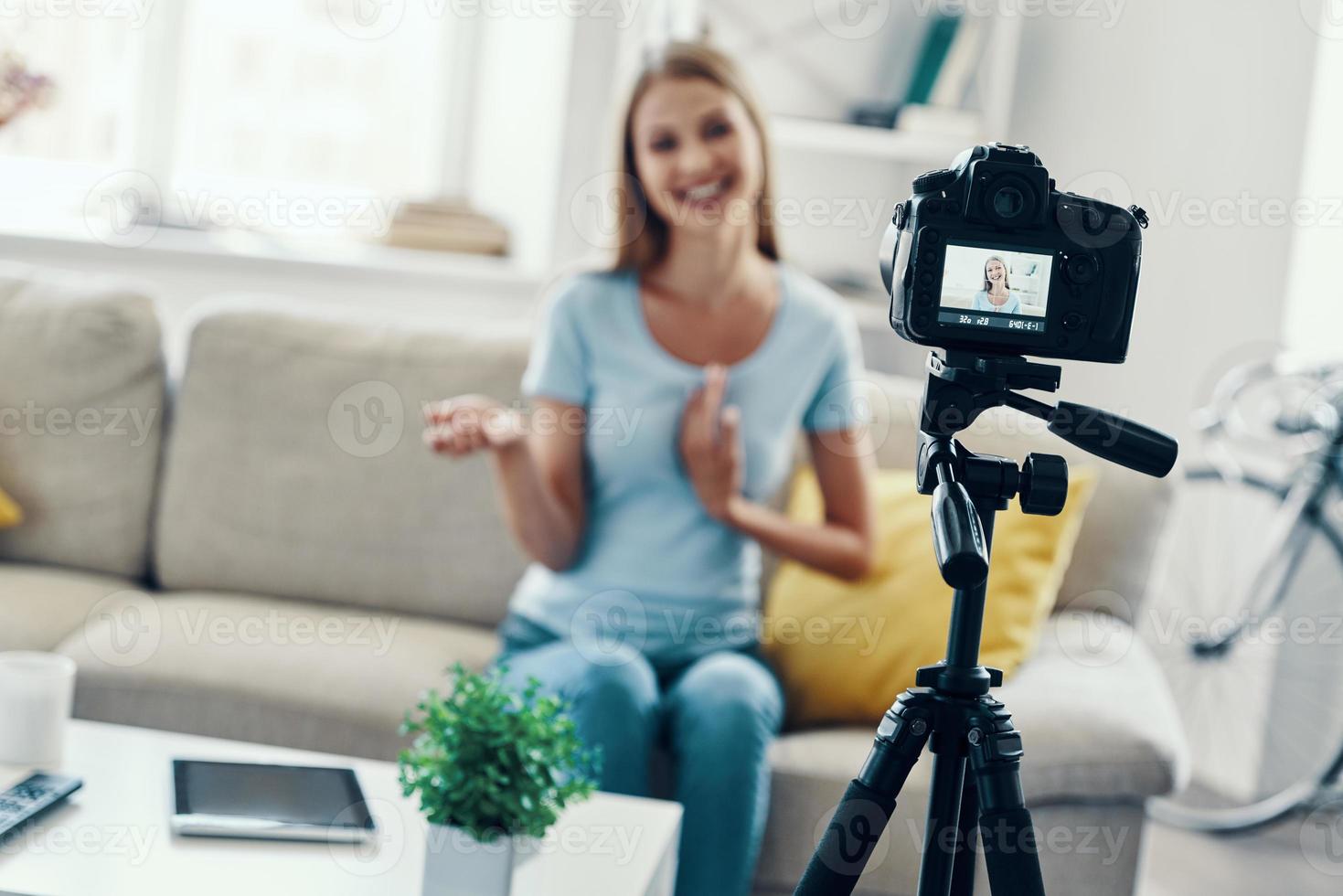 skön ung kvinna leende och gestikulerar medan framställning social media video på Hem foto