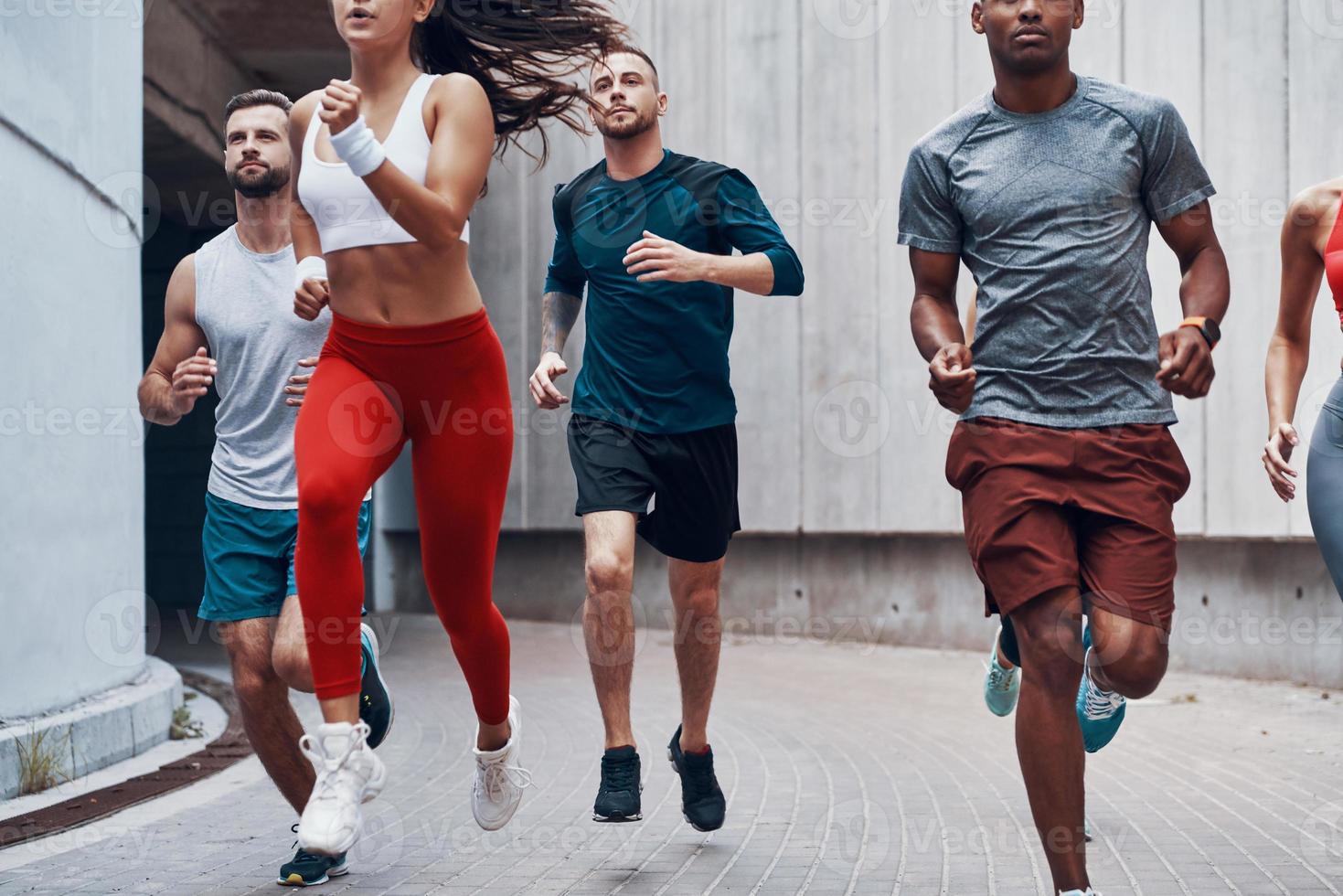 grupp av ung människor i sporter Kläder joggning medan utövar utomhus foto