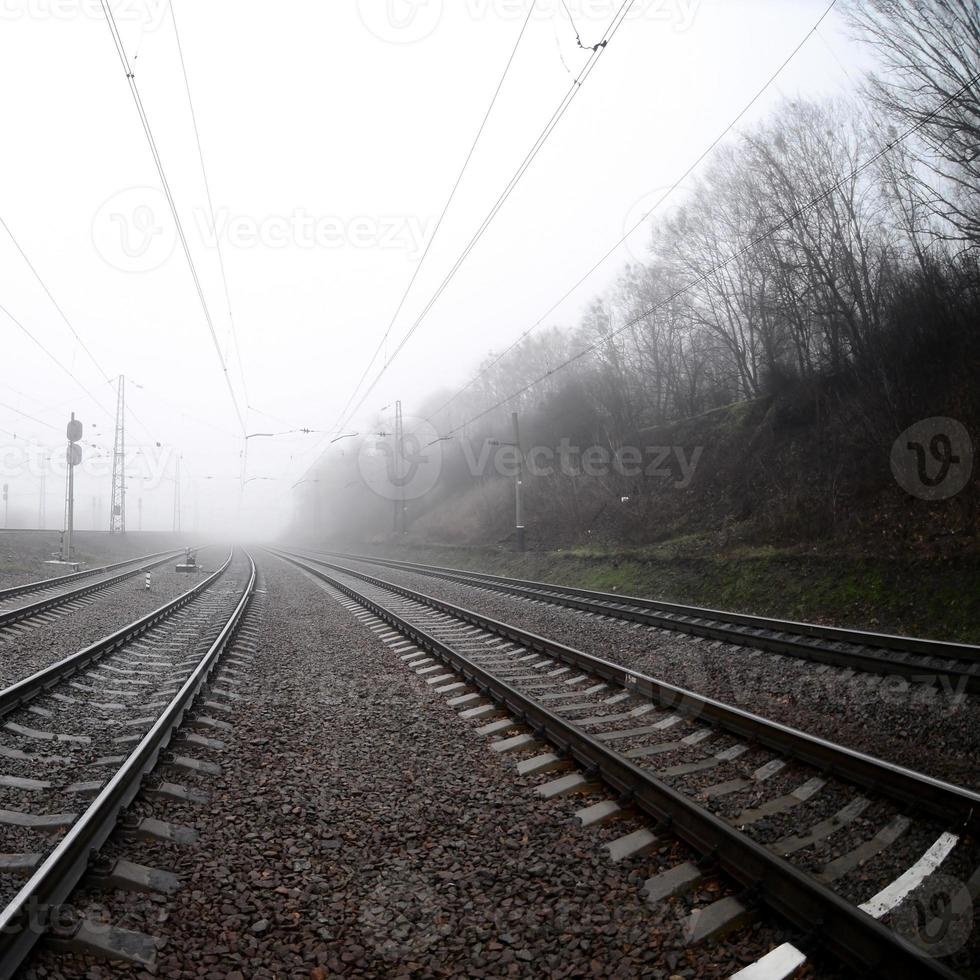 de järnväg Spår i en dimmig morgon. en massa av skenor och sliprar gå in i de dimmig horisont. fisköga Foto med ökade förvrängning