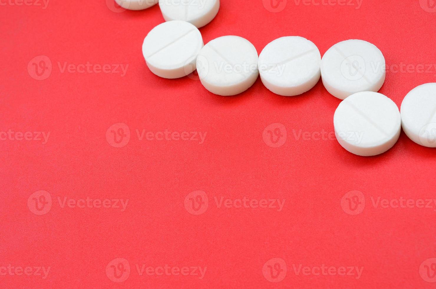 en få vit tabletter lögn på en ljus röd bakgrund yta. bakgrund bild på medicinsk och farmaceutisk ämnen foto