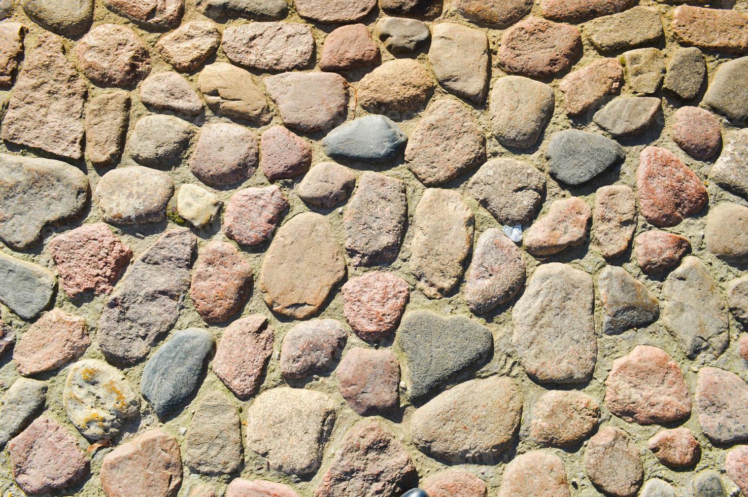 de textur av de sten väg, trottoar, väggar av stor grå gammal medeltida runda stark stenar, kullerstenar. de bakgrund foto