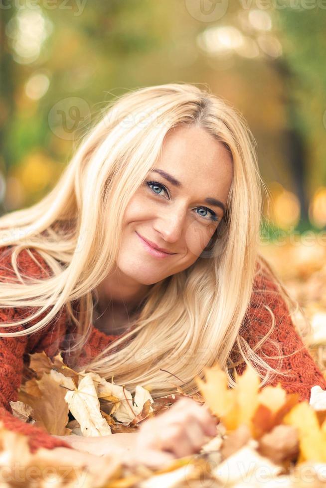 kvinna lögner ner på löv på de höst parkera foto