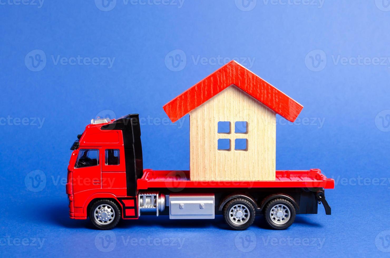 röd lastbil transporter en röd täckt hus. begrepp av transport och frakt frakt, rör på sig företag. konstruktion av ny hus och objekt. industri. logistik och tillförsel. flytta hel byggnader. foto