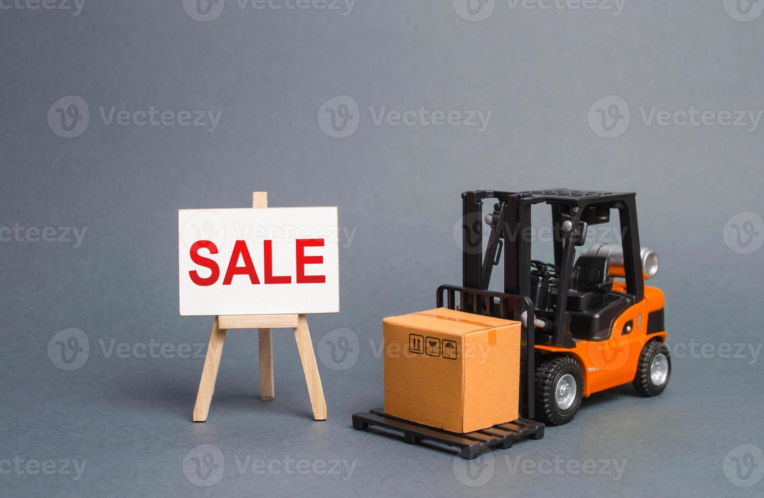 orange gaffeltruck lastbil bär en kartong låda och en stå med en ord försäljning. tillväxt av försäljning. stor rabatter på varor av de utgående säsong. Råvara utbyta med Övrig länder. lockar köpare foto