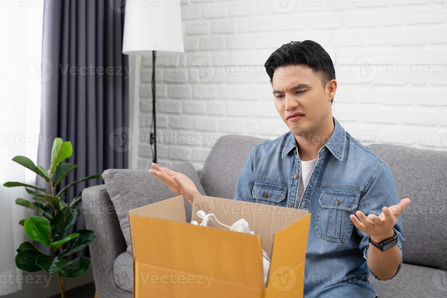 besviken asiatisk kille med kartong paket med beställa från internet uppkopplad Lagra, kopia Plats foto