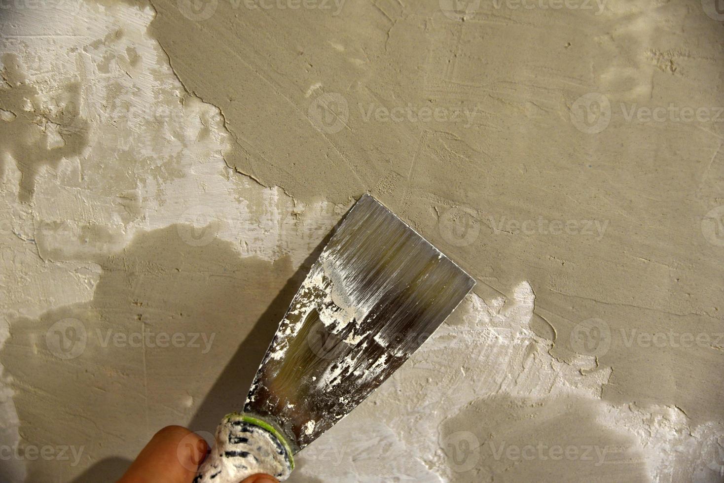 arbete med ett järn spatel när putsning de vägg med en cement lösning. reparera av de vägg med en murslev med cement. foto