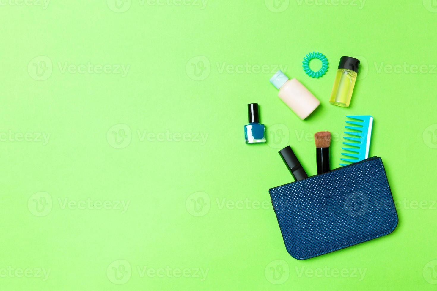 göra upp Produkter spill ut av kosmetika väska på grön bakgrund med tömma Plats för din design foto