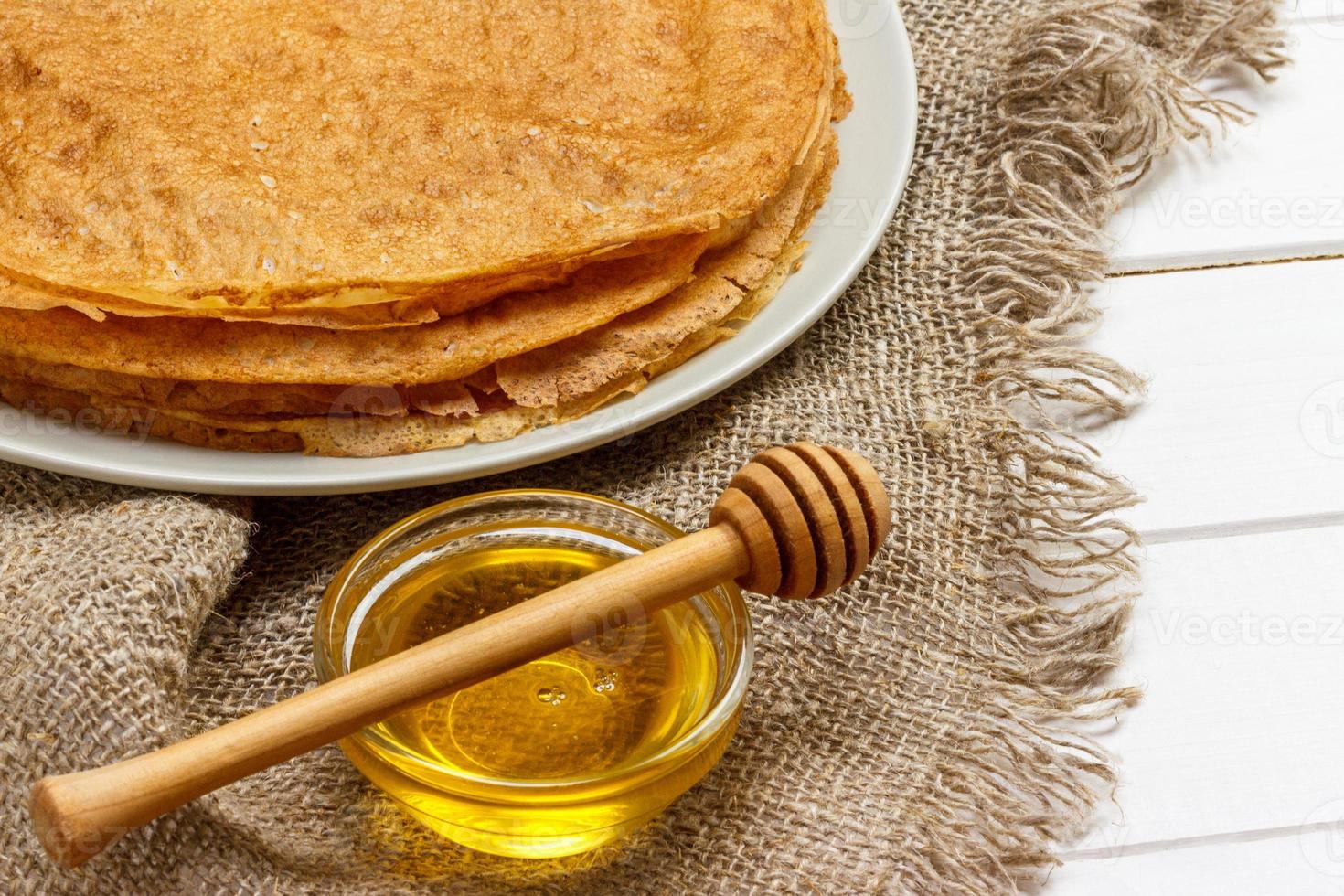 en lugg av pannkakor, honung, för de firande av de karneval. tunn pannkakor för frukost. pannkakor och honung maslenitsa. pannkakor med honung på en vit trä- bakgrund. Plats för text foto