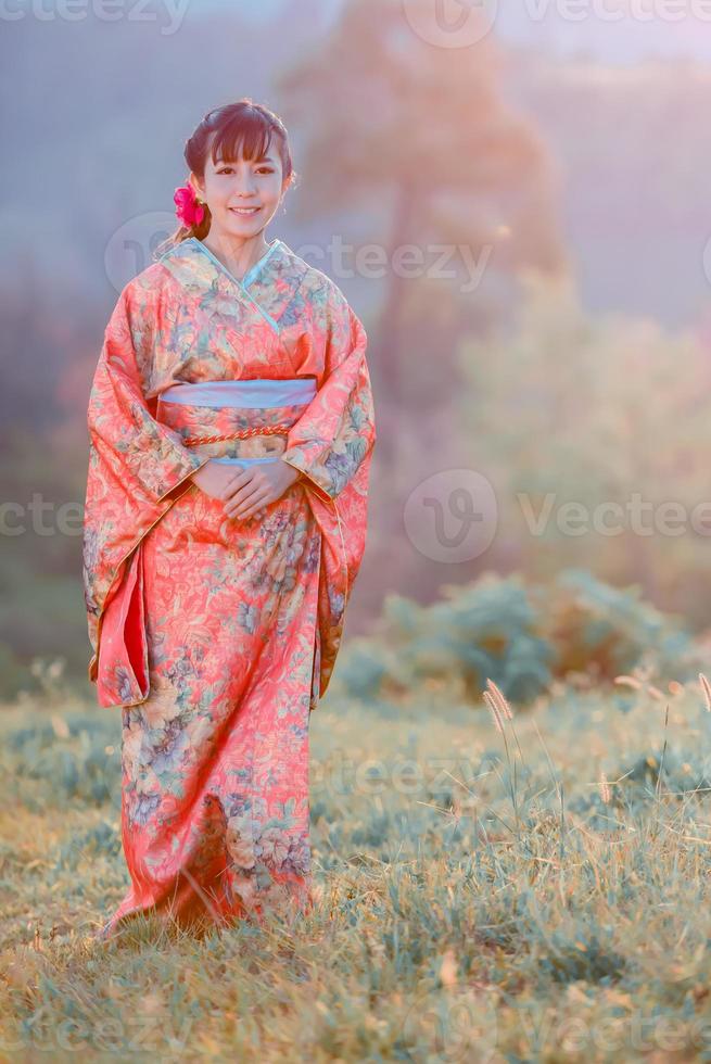 resa , semester i japan begrepp, ung asiatisk kvinna bär traditionell japansk kimono i de parkera i de morgon. foto