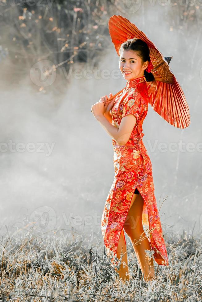 resa , semester i japan begrepp, ung asiatisk kvinna bär röd traditionell japansk kimono och innehav paraply i de parkera i de morgon. foto