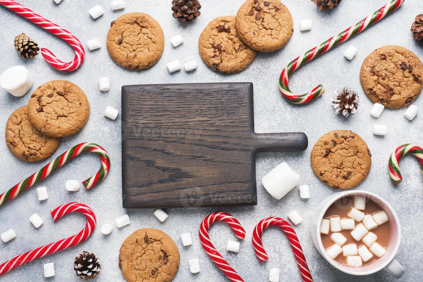 de choklad chip kaka, jul sockerrör kola kopp kakao och marshmallow koner dekorationer på en grå bakgrund. kopia Plats ram. foto