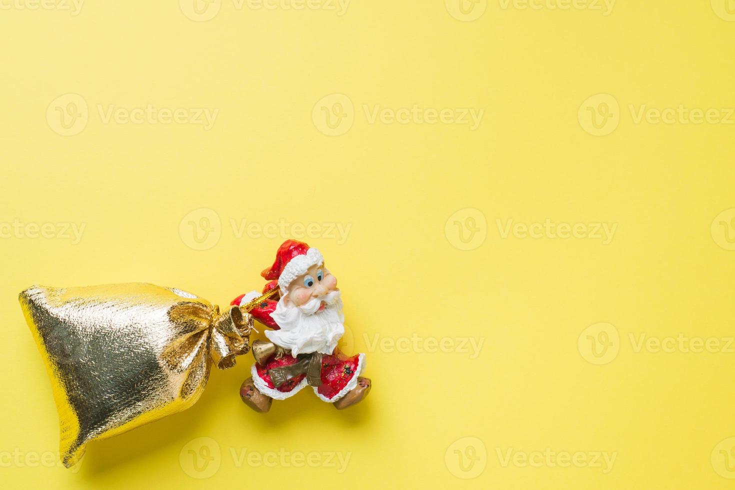 en leksak santa med en guld säck av gåvor på gul bakgrund med kopia Plats. de begrepp av jul ny år. foto