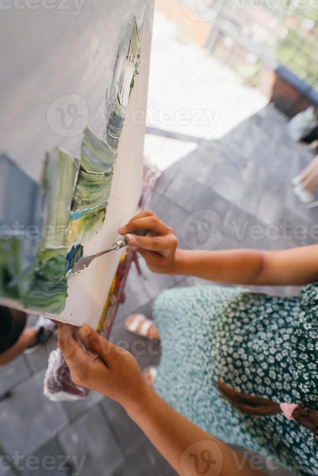 närbild av kvinnas hand applicering måla till en duk foto