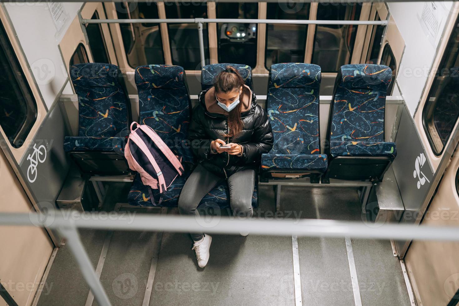 ung kvinna med mask reser i de offentlig transport. foto