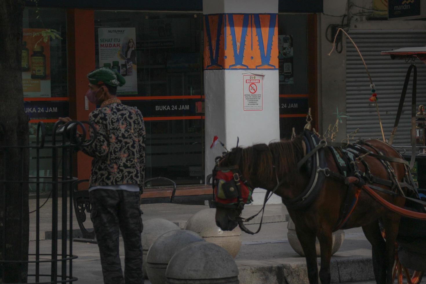 yogyakarta, indonesien på oktober 23, 2022. andong eller hästdragen transport med dess kusk parkerad på jalan malioboro, väntar för passagerare. foto