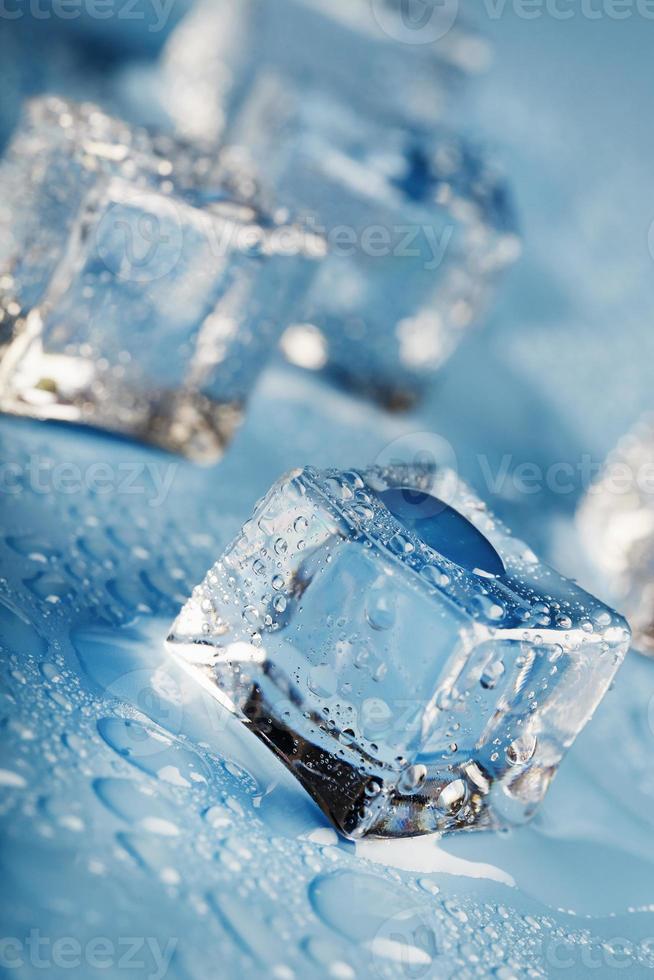 närbild is kuber med smälta vatten droppar spridd på en blå bakgrund. foto