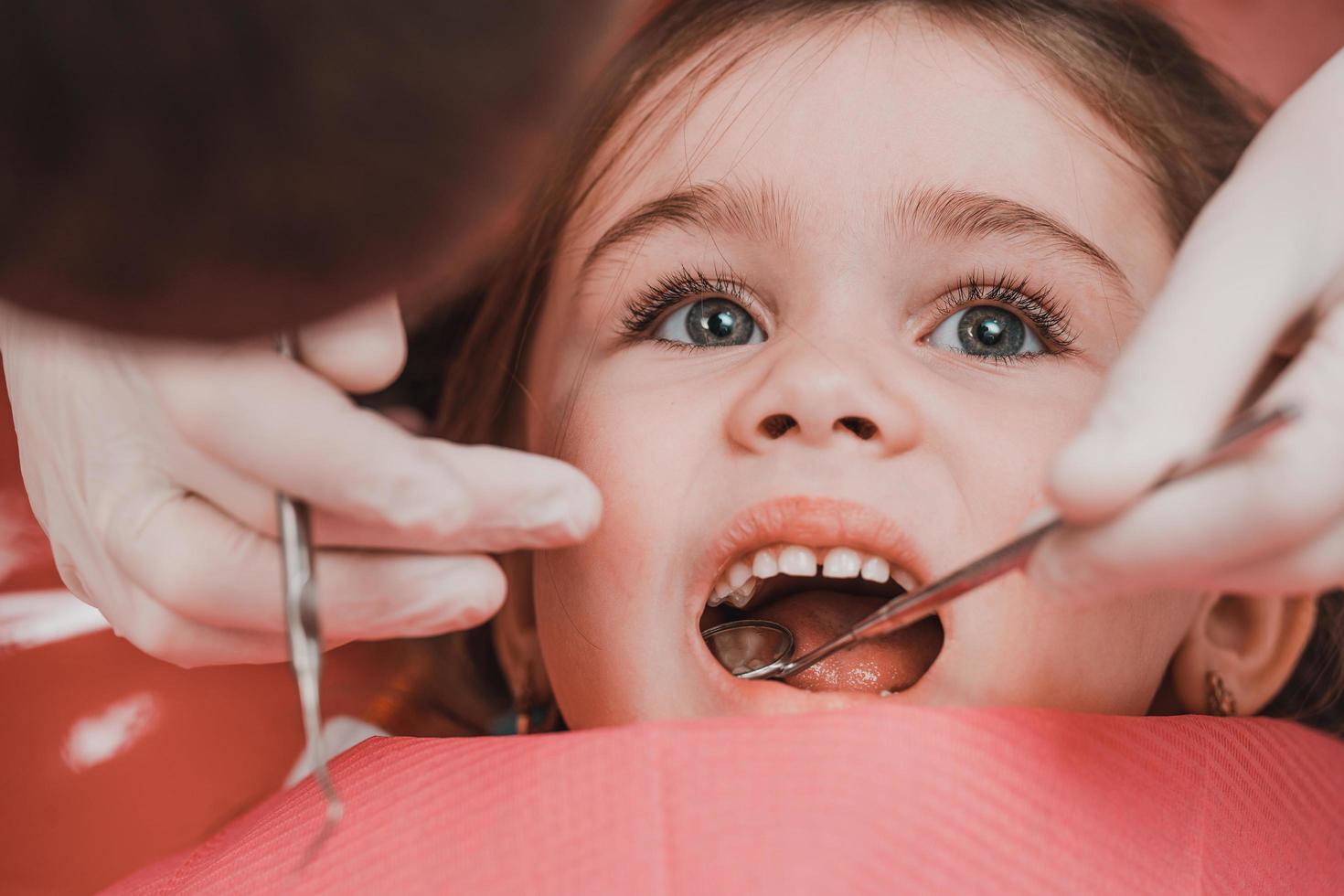 behandling av bebis tänder i en barn, en liten flicka på de tandläkare, undersökning och behandling av tänder. foto