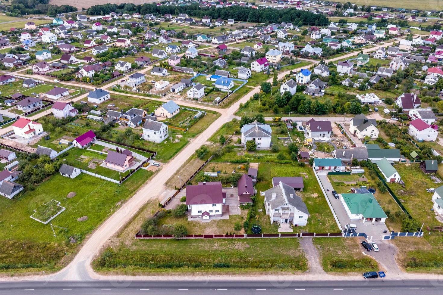 panoramautsikt över den gröna byn med hus, lador och grusväg i skogen foto