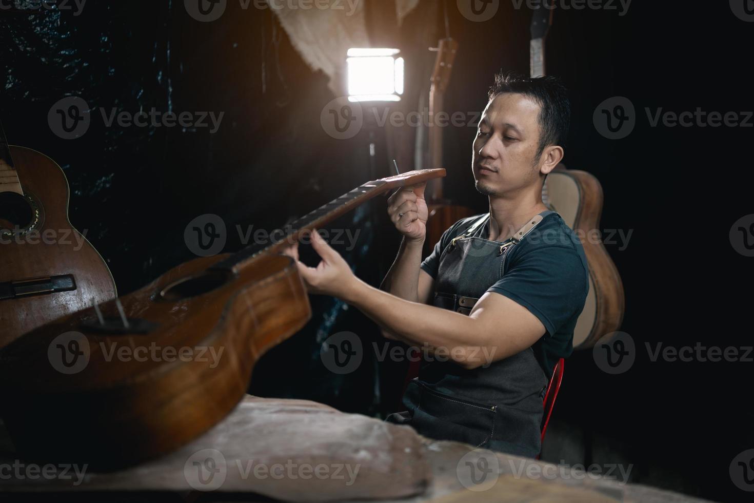 gitarr tillverkare asiatisk man framställning akustisk gitarrer i laboratorium. asiatisk gitarr tillverkare bygger hög kvalitet gitarrer för musiker handgjort gitarr affär. arbetssätt bra trämusik, tradition, gammal hantverk. foto