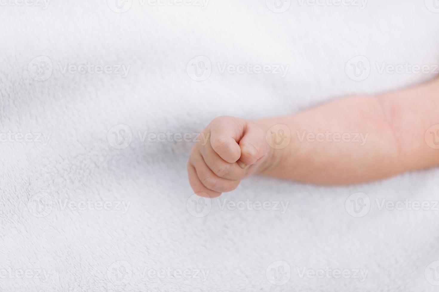 närbild av nyfödd bebis flicka hand på vit filt utomhus. moderskap och barndom begrepp. selektiv fokus foto