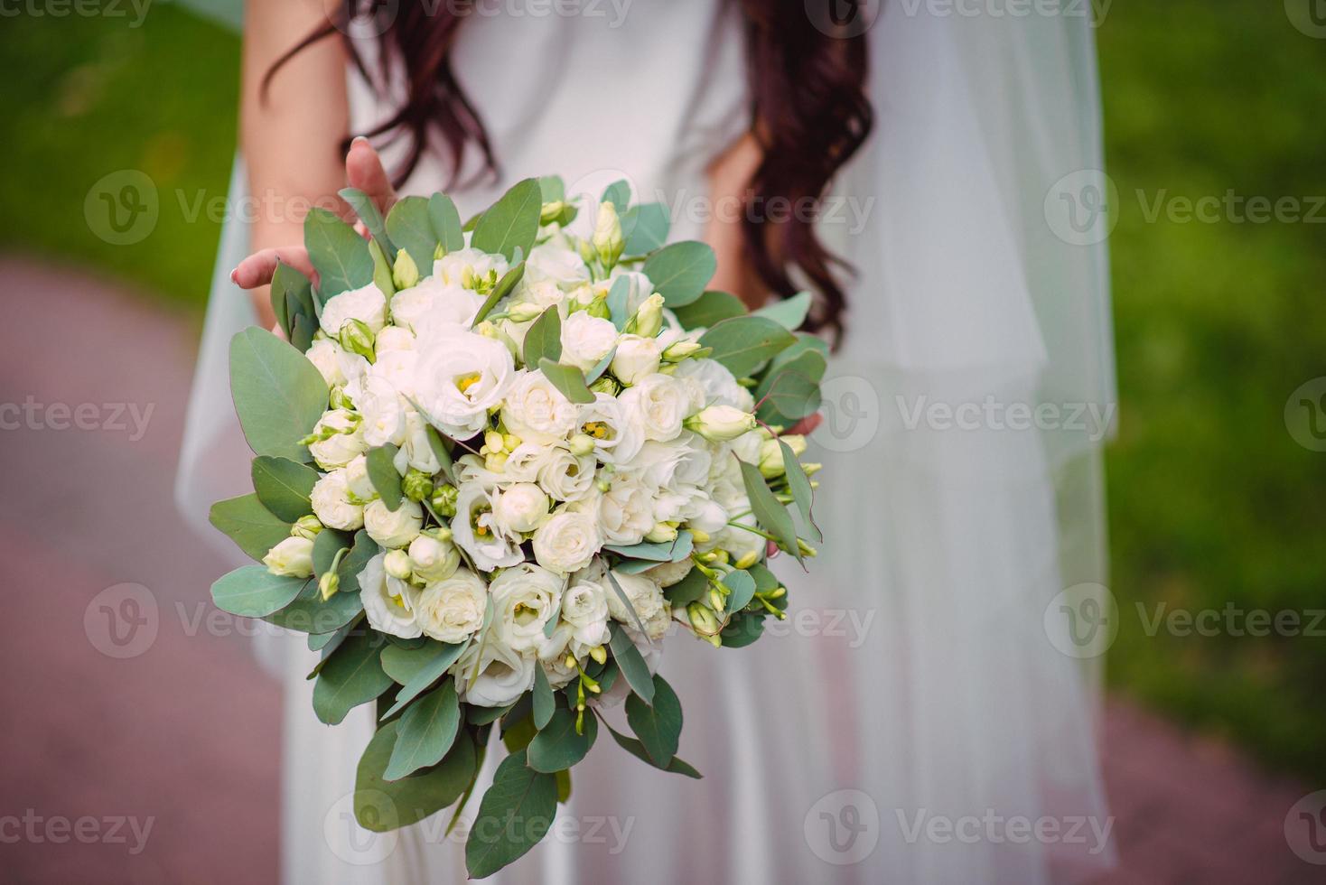 de brud innehar en bröllop bukett i henne händer, bröllop dag blommor. foto