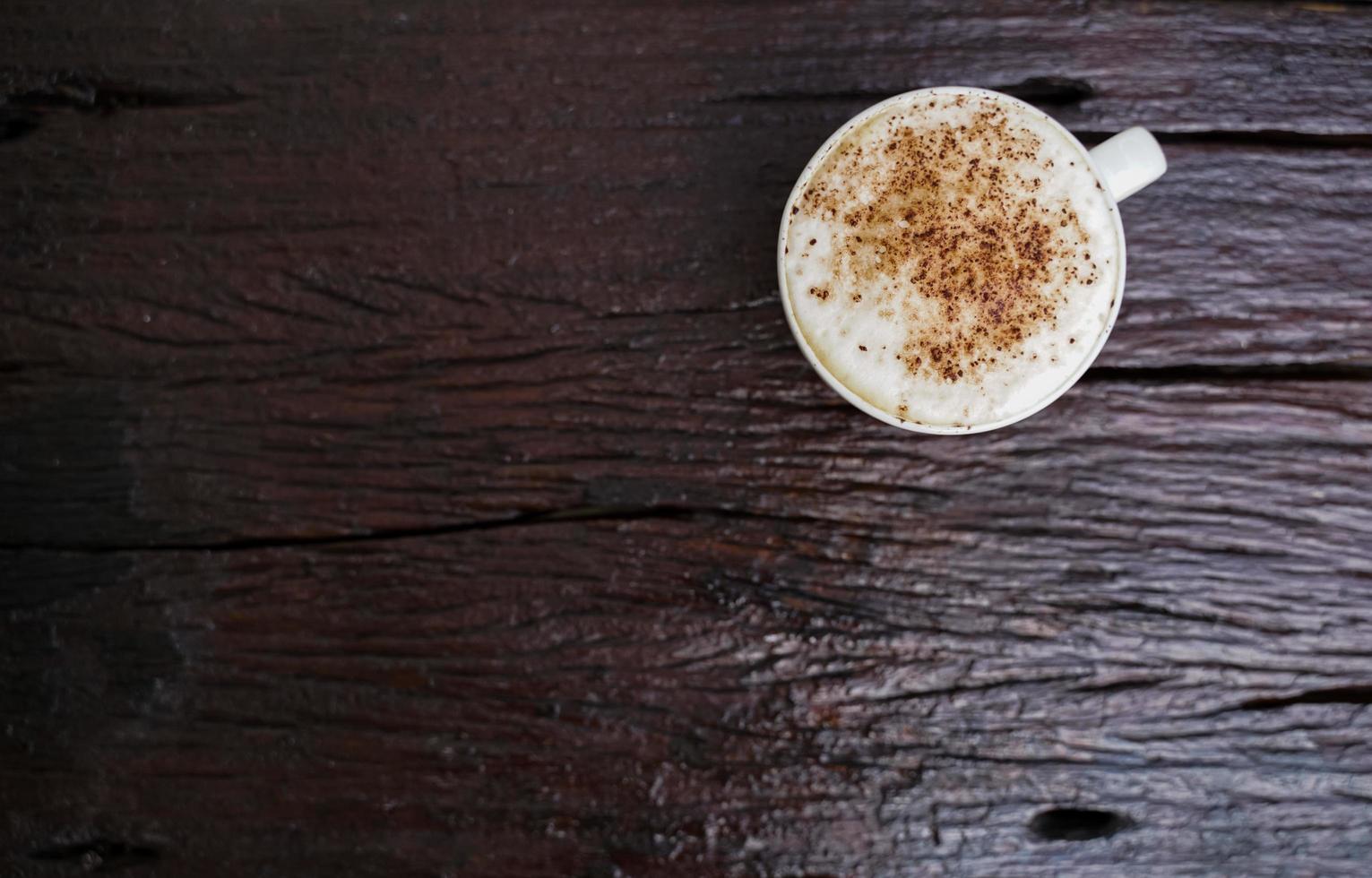 varm cappuccino i vit kopp med trä- bakgrund, kaffe är en populär dryck Allt över de värld. foto