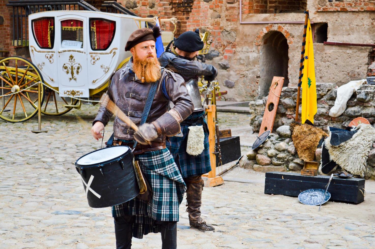 en skott krigare, soldat, musiker med en röd skägg i traditionell kostym med en kjol takter de trumma på de fyrkant av en medeltida gammal slott. nesvizh, belarus, oktober 12, 2018 foto