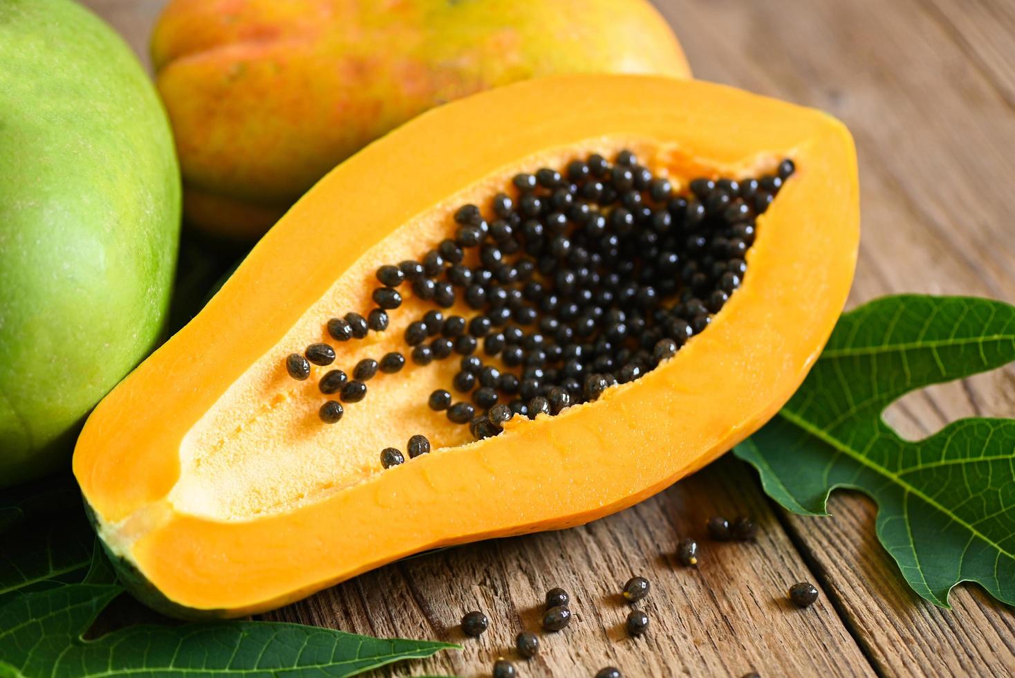 papaya frukt på trä- bakgrund, färsk mogen papaya tropisk frukt med papaya utsäde och blad löv från papaya träd foto