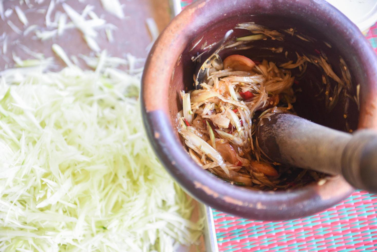 papaya sallad thai mat stil asiatisk - kokta grön papaya strimlad med ingrediens örter och kryddor i murbruk foto