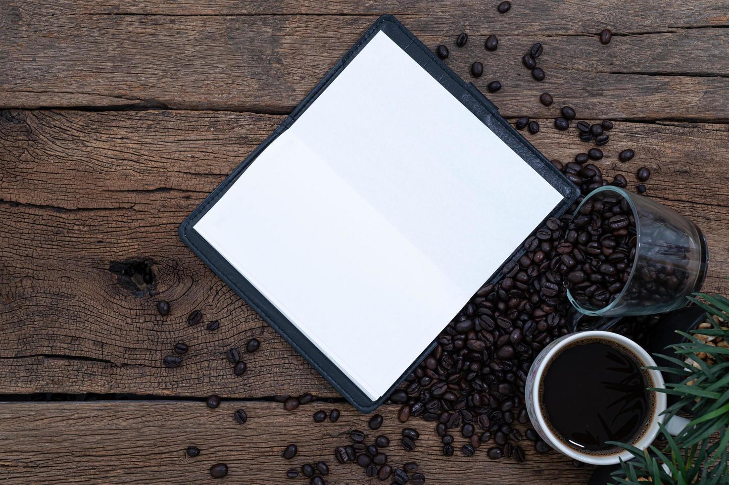 kaffemuggar, kaffebönor och en skivbok foto