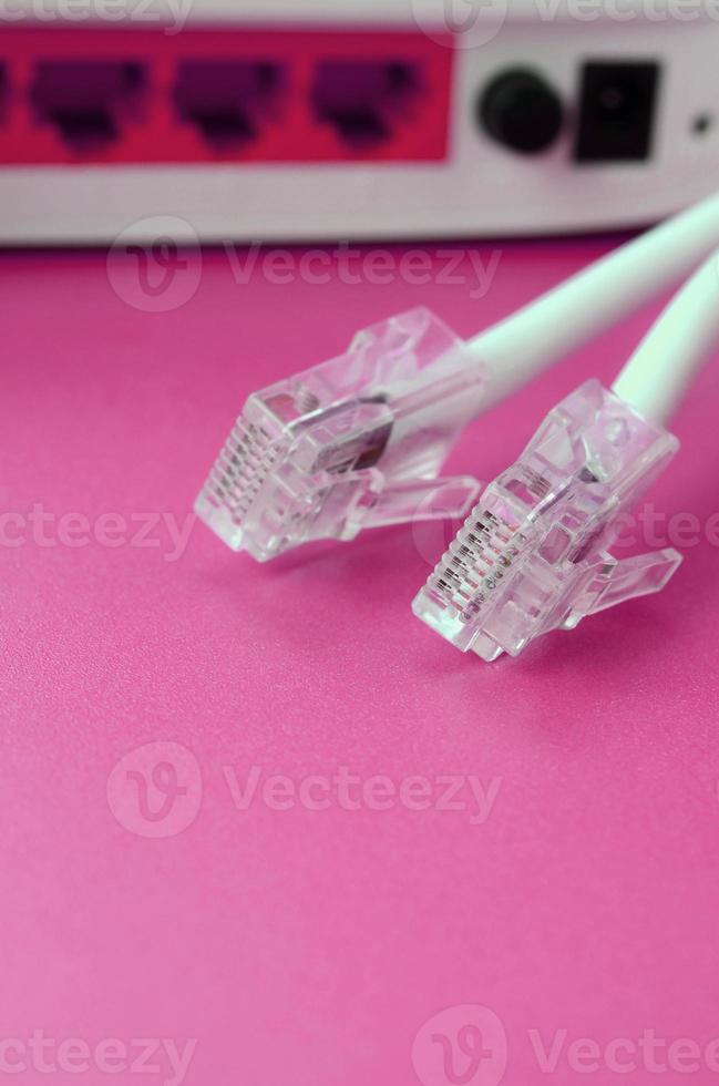 internet router och internet kabel- pluggar lögn på en ljus rosa bakgrund. objekt nödvändig för internet foto