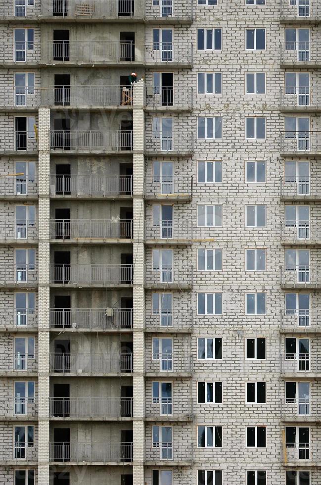 texturerad mönster av en ryska vit sten bostads- hus byggnad vägg med många fönster och balkong under konstruktion foto