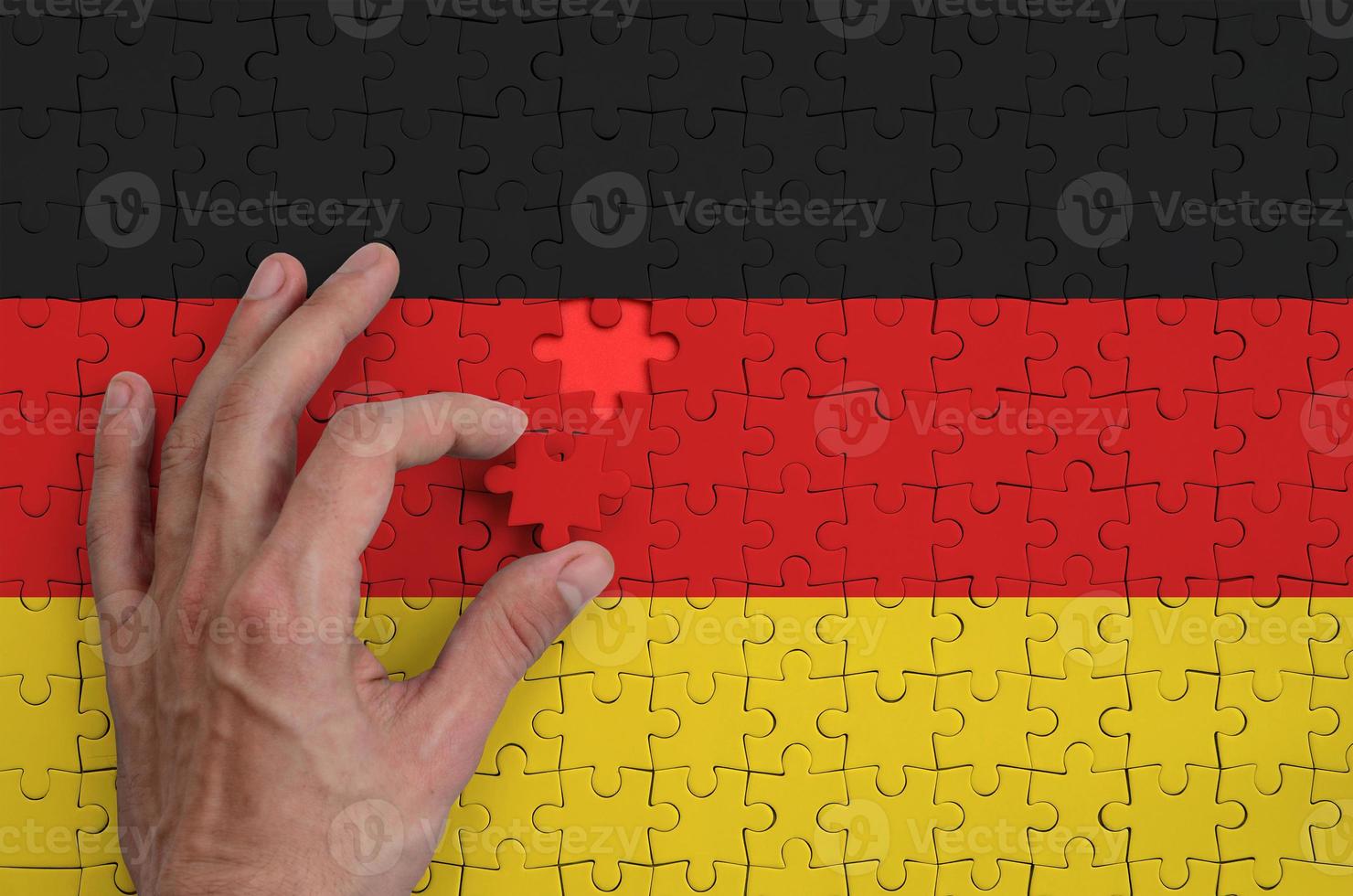 Tyskland flagga är avbildad på en pussel, som de mannens hand slutförs till vika ihop foto