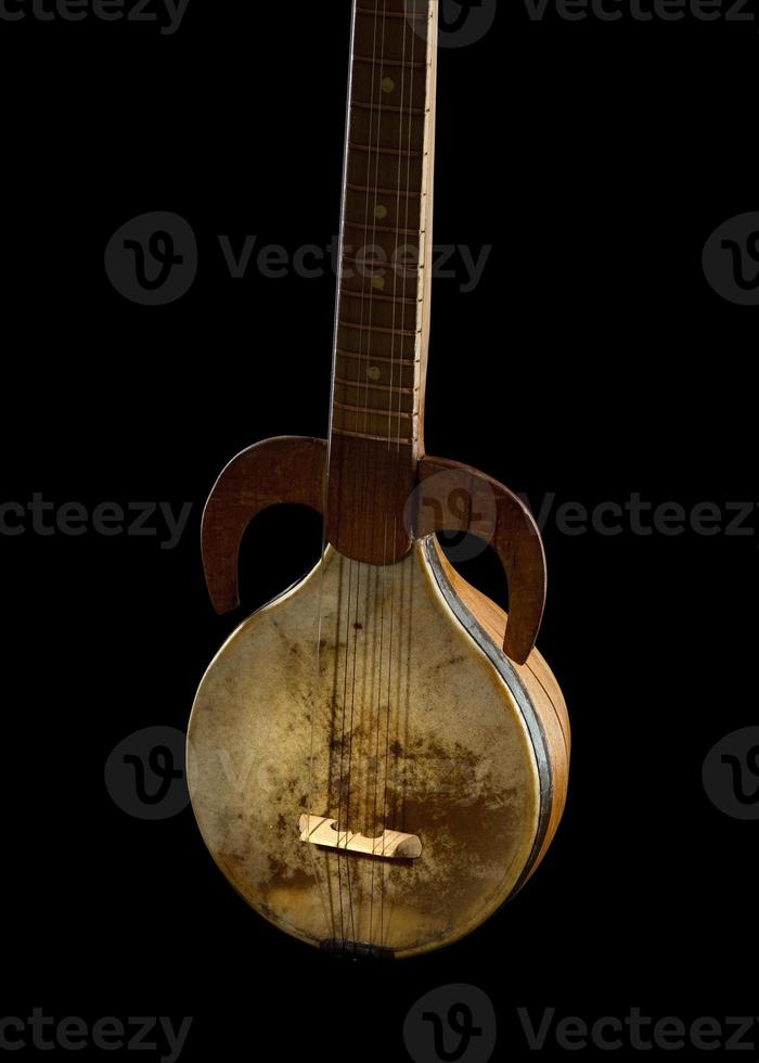 ett gammal asiatisk strängad musikalisk instrument på en svart bakgrund foto
