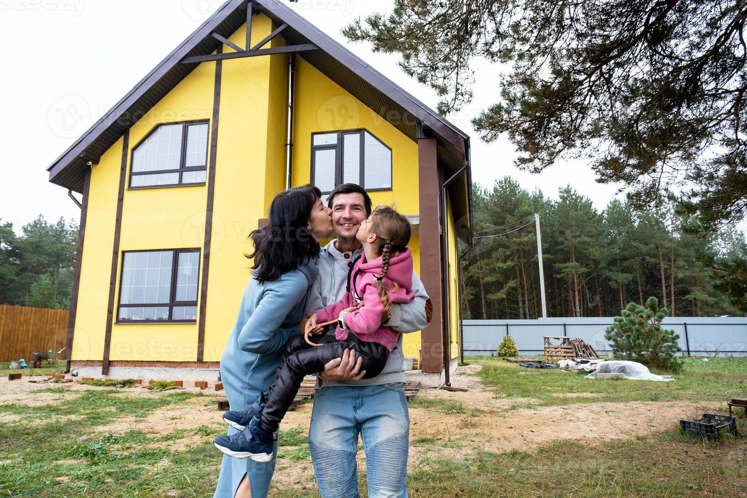 Lycklig familj i de gård av ett oavslutat hus - inköp av en stuga, inteckning, lån, flytt, konstruktion foto