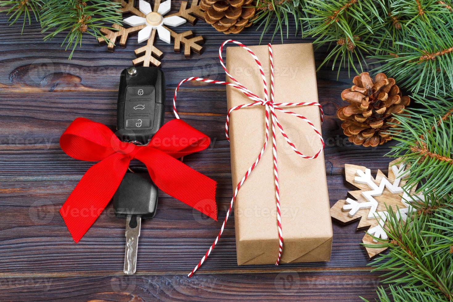 bil nyckel med färgrik rosett med gåva låda och jul dekoration på trä- bakgrund foto