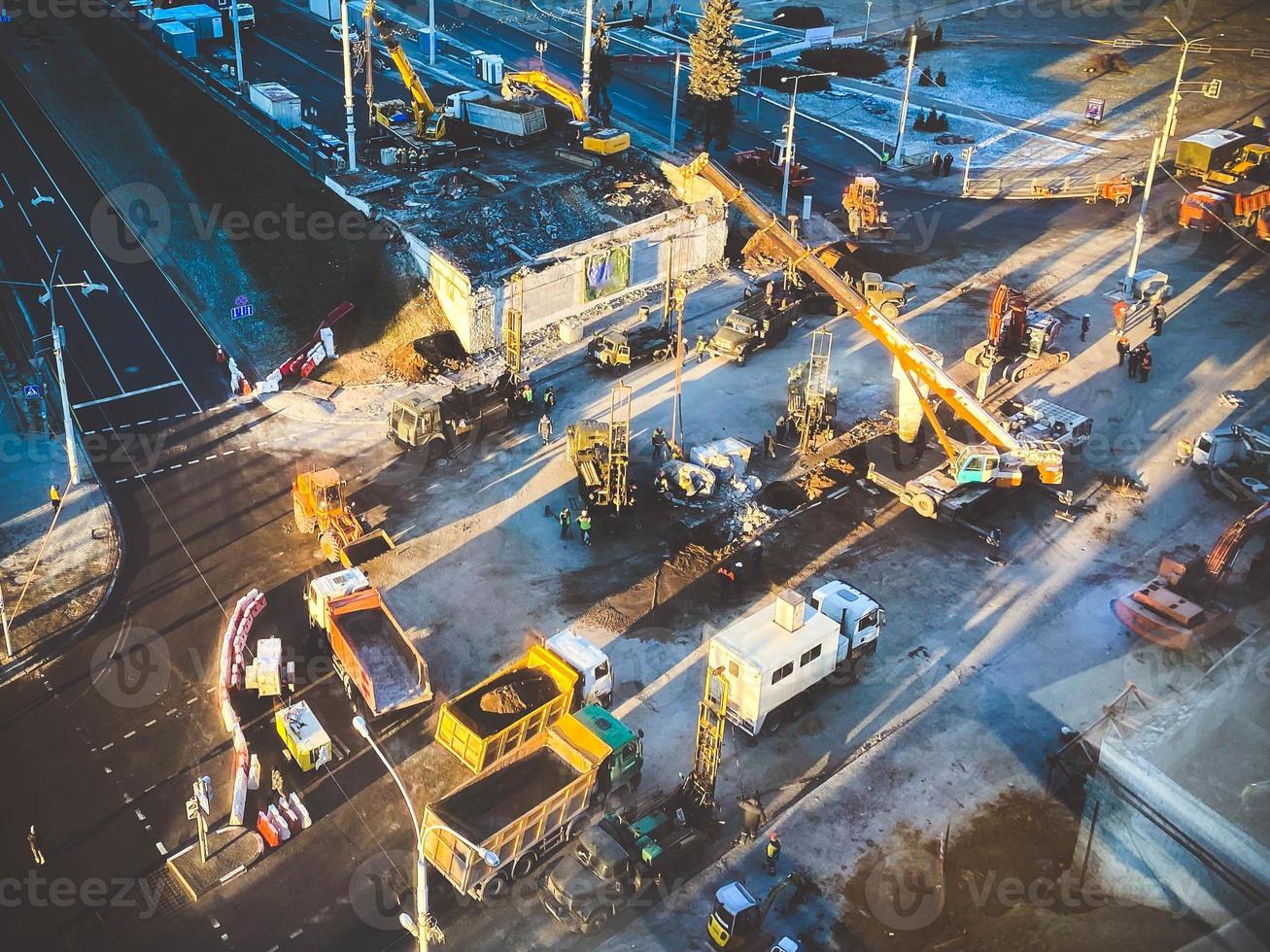 konstruktion av en ny planskild i de stad Centrum på en snöig gata. väg reparera, enorm, tung fordon bära och bära byggnad material foto