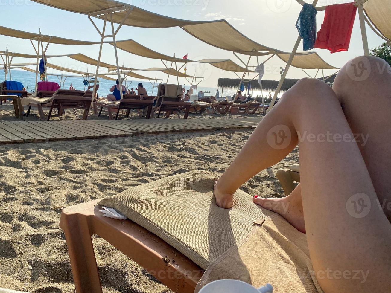 ben av en vilar kvinna turist flicka på de strand och Sol solstolar, paraplyer och fåtöljer i de hotell och de hav i en värma tropisk östra paradis Land sydlig tillflykt foto