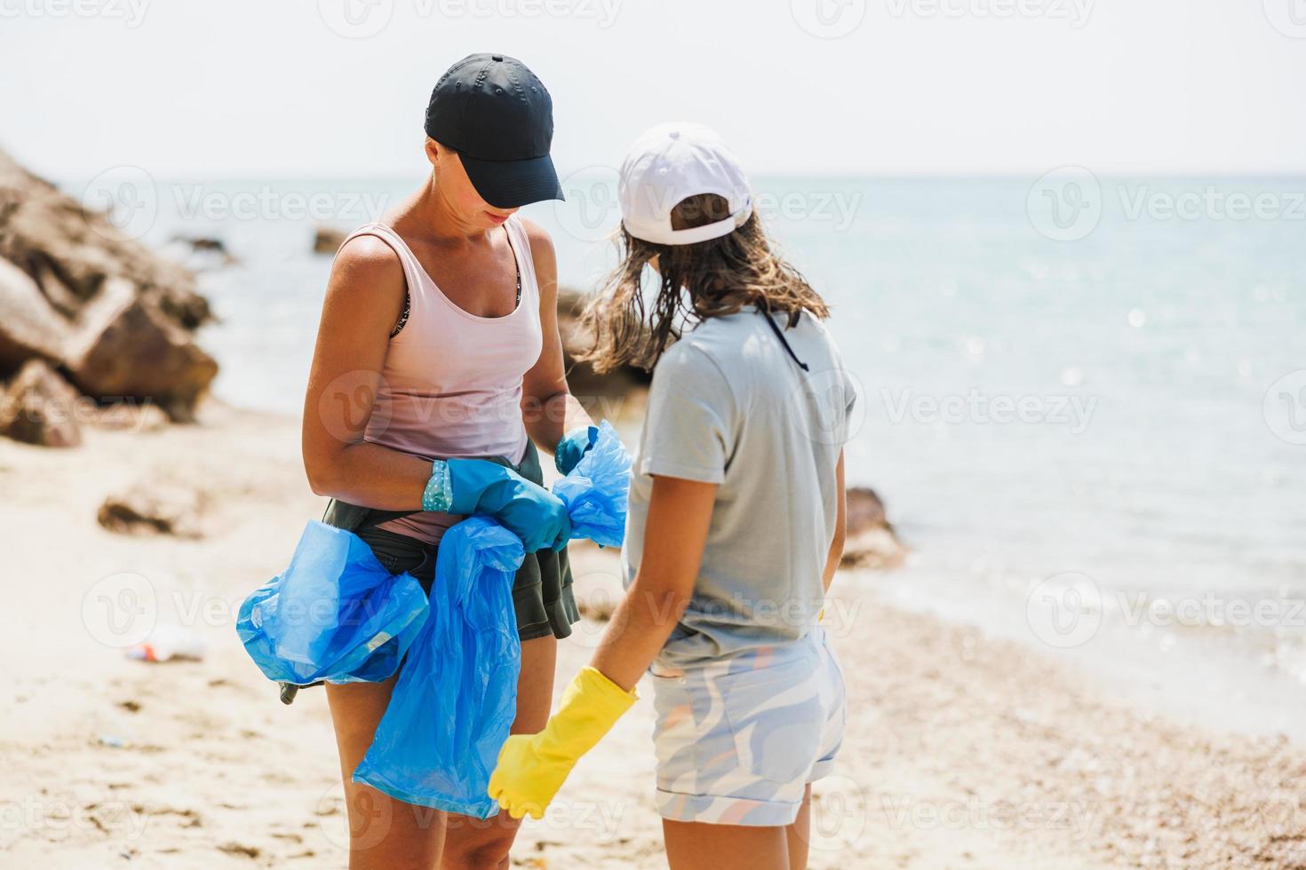 två kvinnor volontärer rengöring upp de strand foto