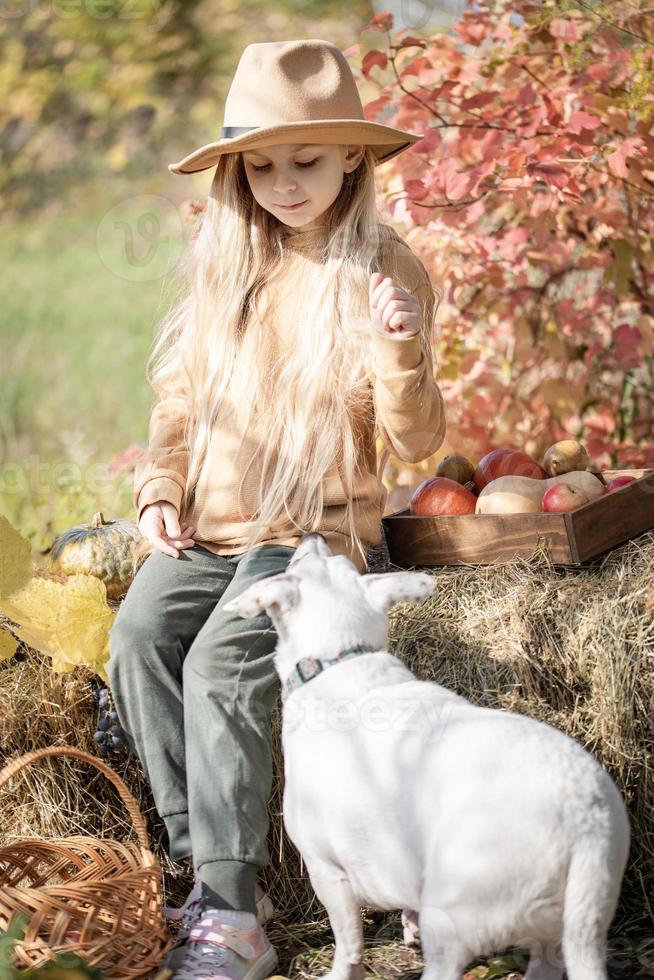 liten flicka spelar med hund i höst trädgård foto